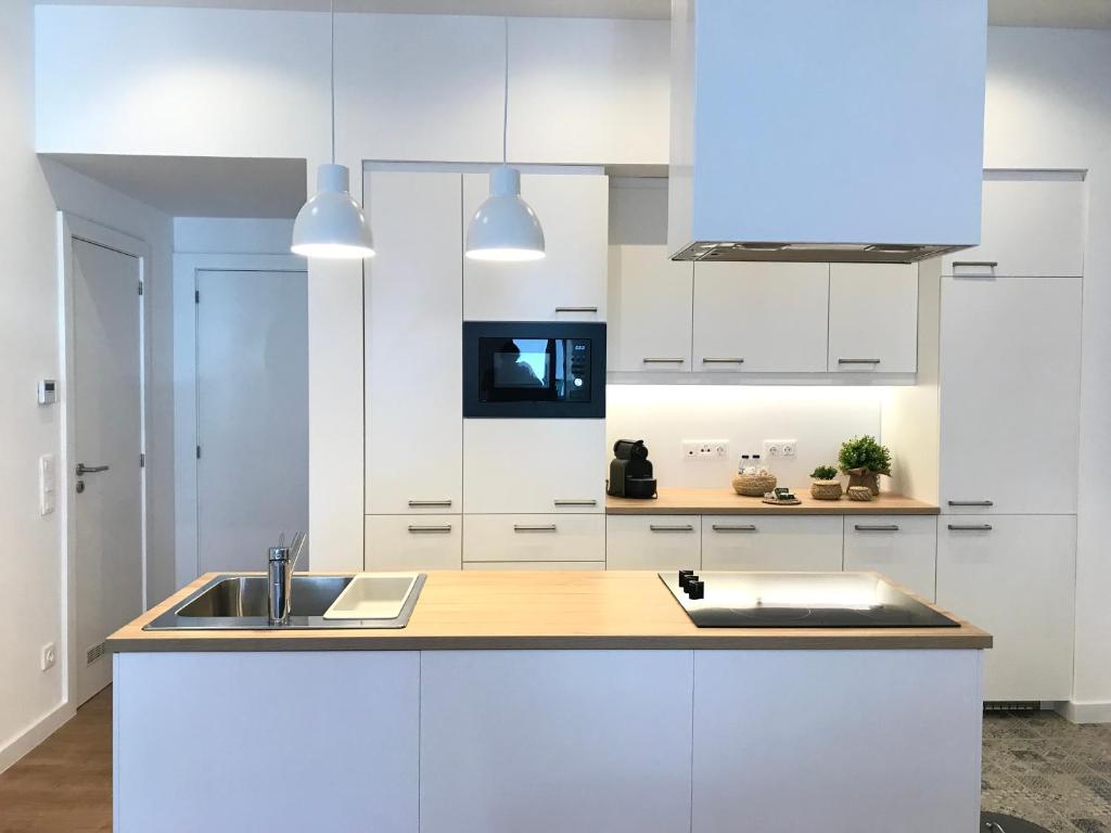 a kitchen with white cabinets and a sink at MyTrip Porto in Matosinhos