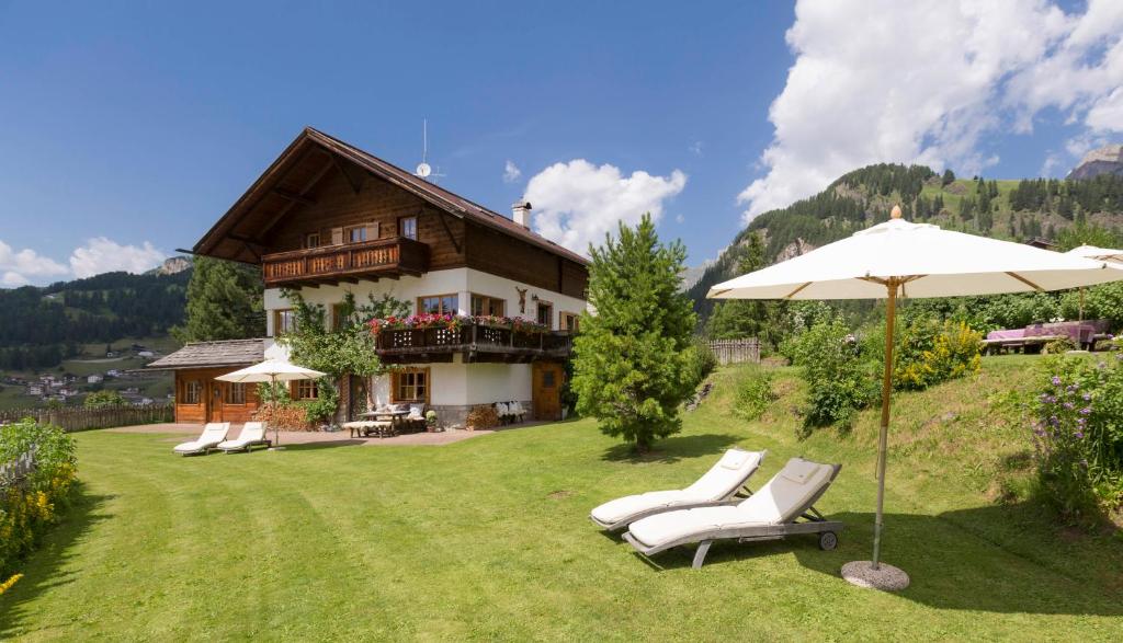 a house with chairs and an umbrella in the yard at Villa al Bosco in Selva di Val Gardena