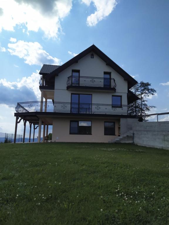 uma casa com um deque no topo de um campo de relva em Cicha Chata Kudłacze em Pcim