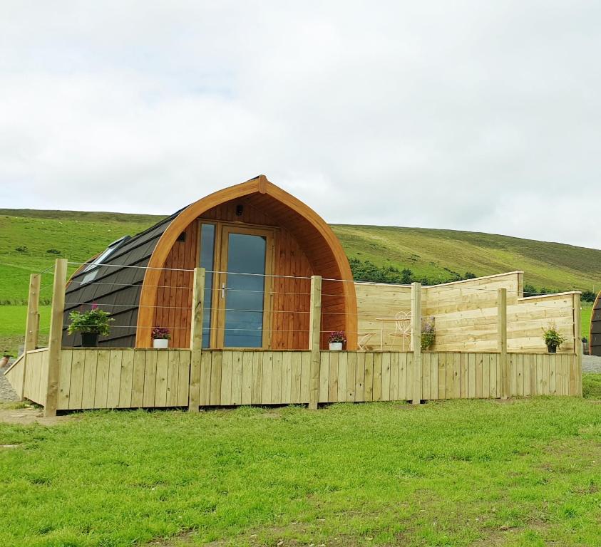 a igloo house in a field with a wooden fence at Lilly's Lodges Orkney Hedgehog Lodge in Finstown