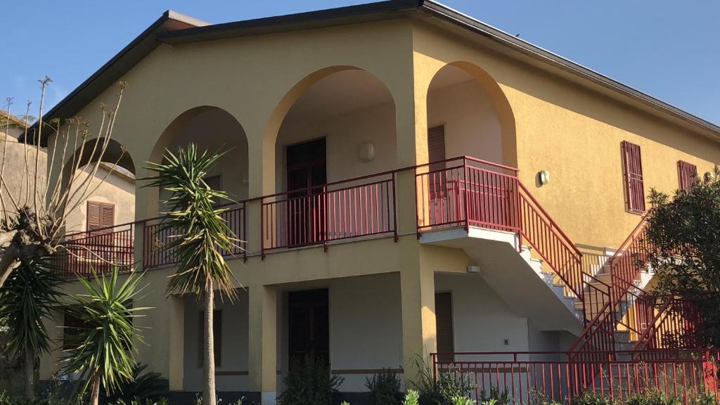 un bâtiment avec des balcons rouges sur son côté dans l'établissement Villa Augustea, à Alcamo