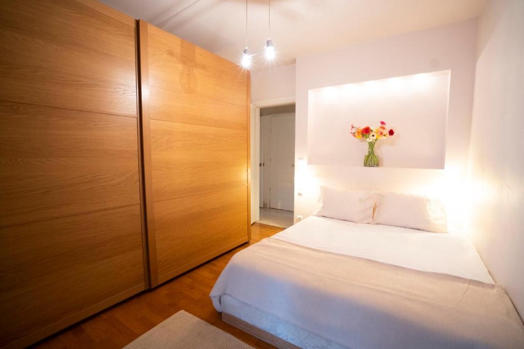 Marousi Luxury Apartment في أثينا: غرفة نوم بسرير و إناء من الزهور