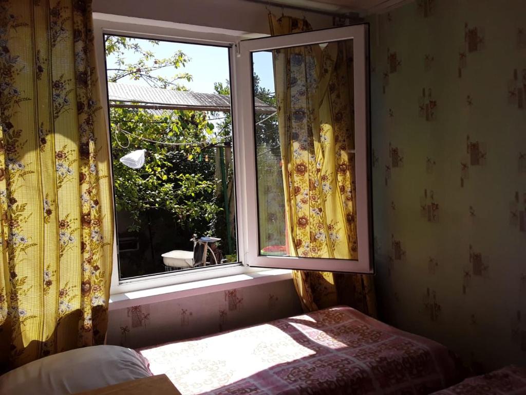 ein Fenster in einem Zimmer mit einem Bett davor in der Unterkunft Zeleniy Dvorik Guest House in Novy Afon