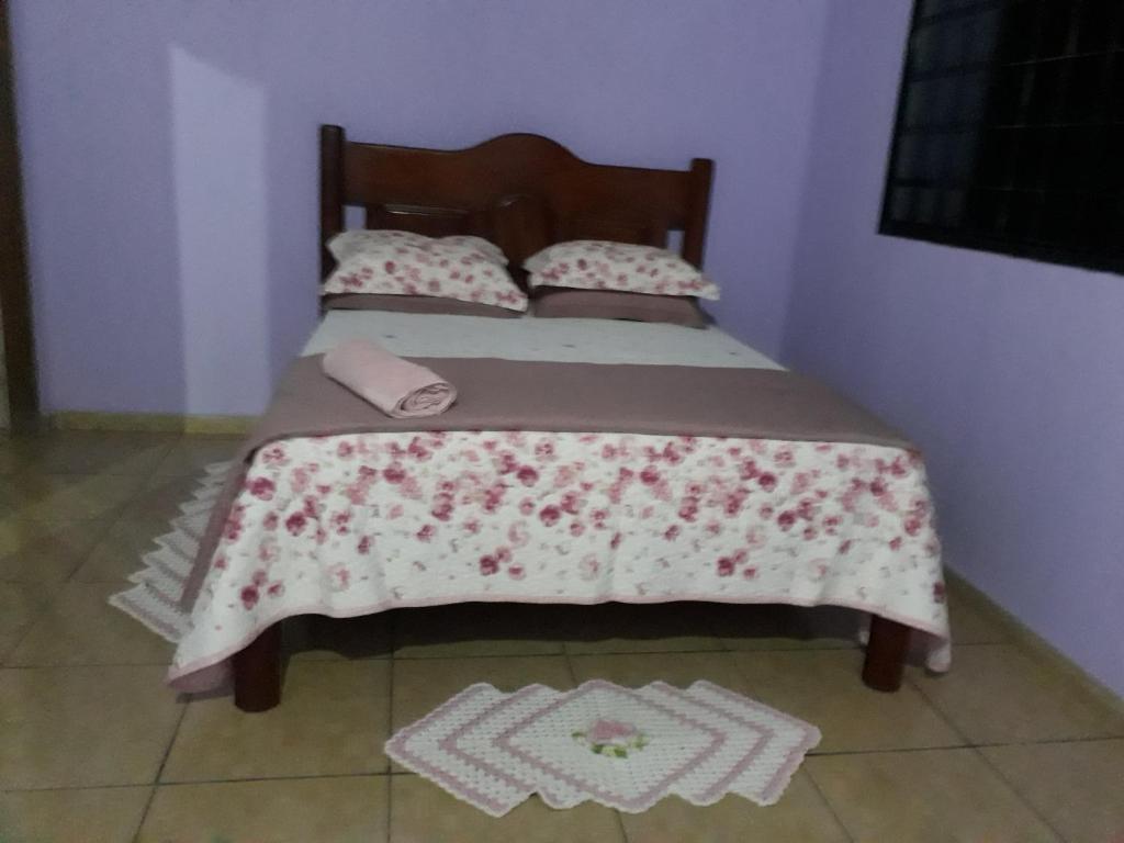 a bed with a bedspread with flowers on it at Pousada Fora de Rota in Colinas Do Sul