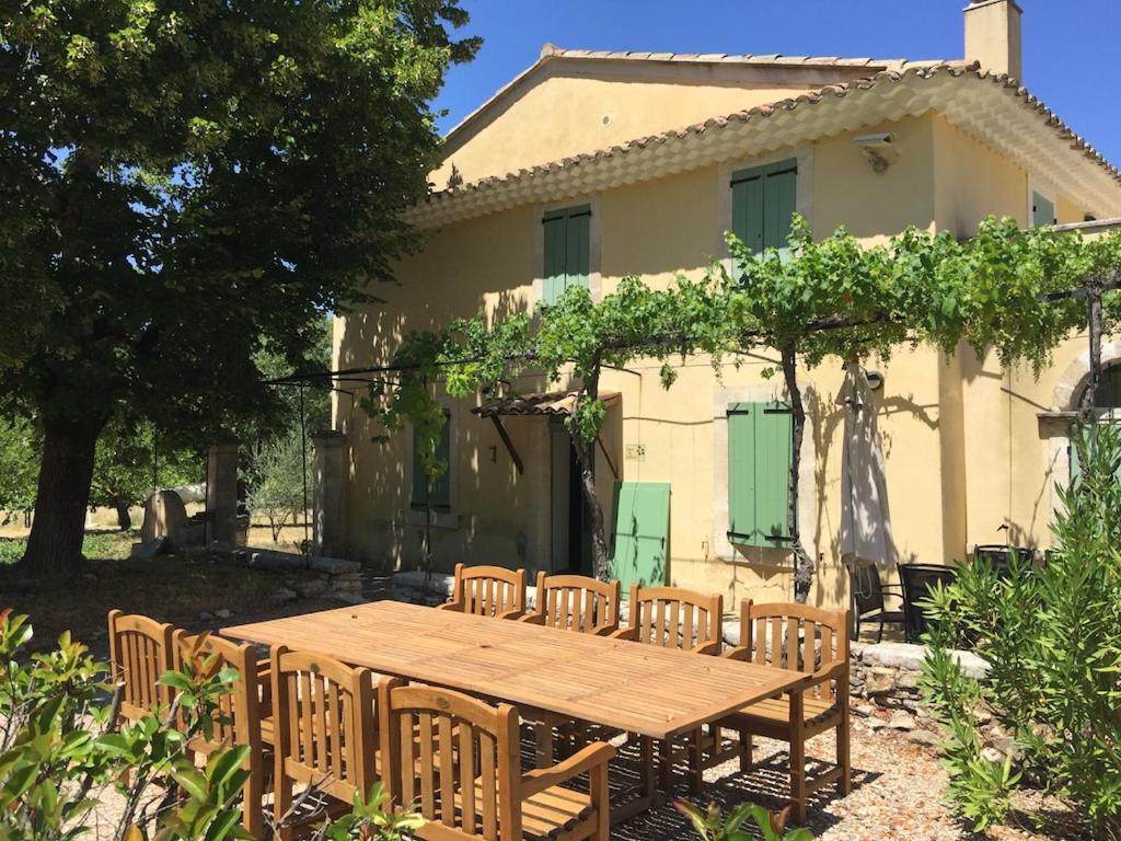 uma mesa de madeira e cadeiras em frente a uma casa em Gîte Tilleul - Bastide Casa mira - domaine d Esclatesang em Apt