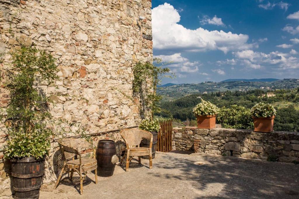 een patio met 2 stoelen en een stenen muur bij Il Melarancio Country House in Scandicci
