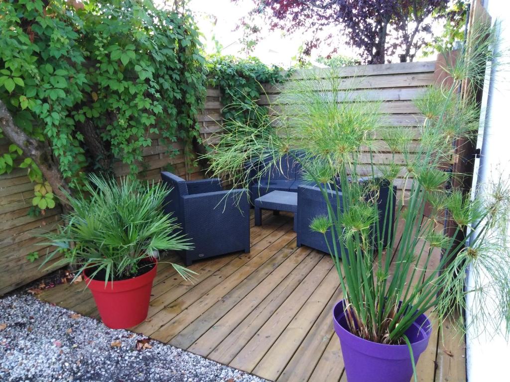 a patio with potted plants on a wooden deck at Appart Terrasse Végétale bord Plages bassin in Arès