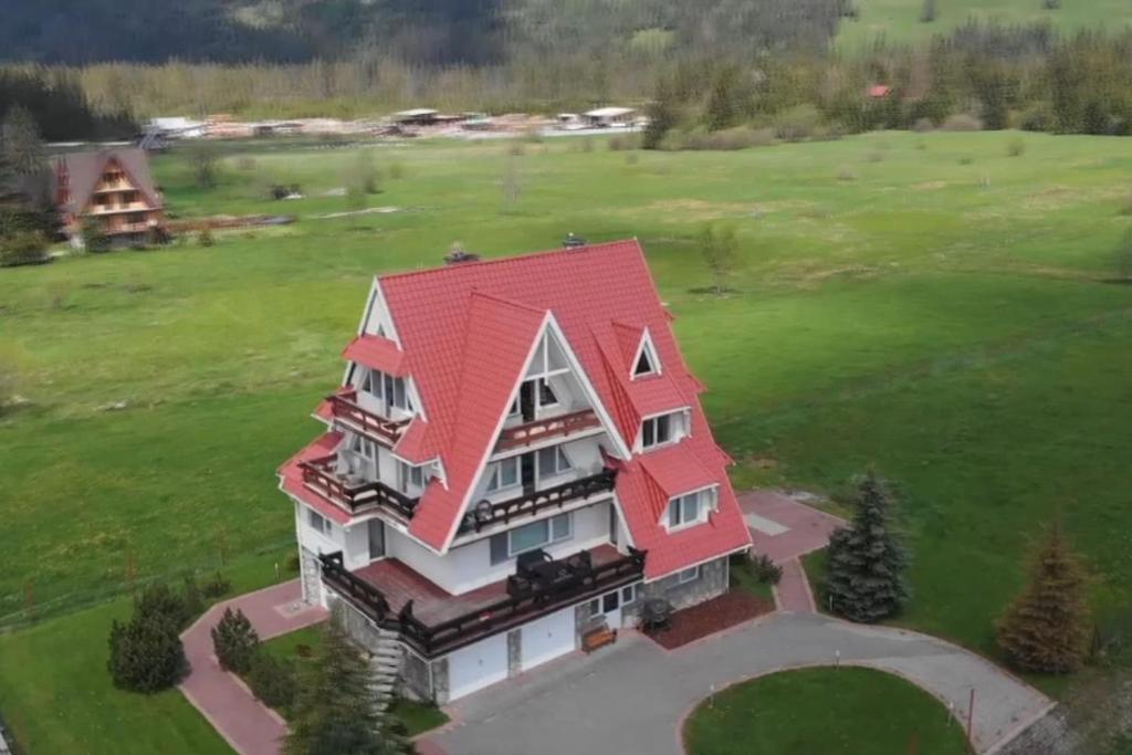 an aerial view of a large house with a red roof at Teddy Deluxe Apartments Zakopane Murzasichle in a quiet neighborhood in Murzasichle