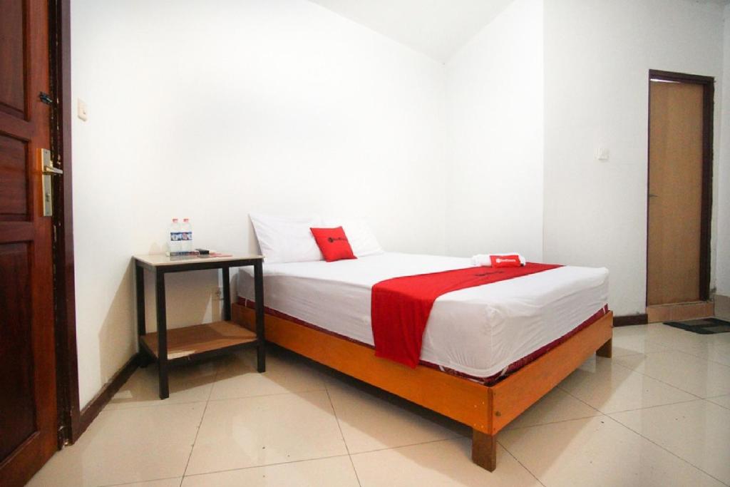 a bedroom with a bed with a red blanket on it at RedDoorz near Mal Abepura in Jayapura