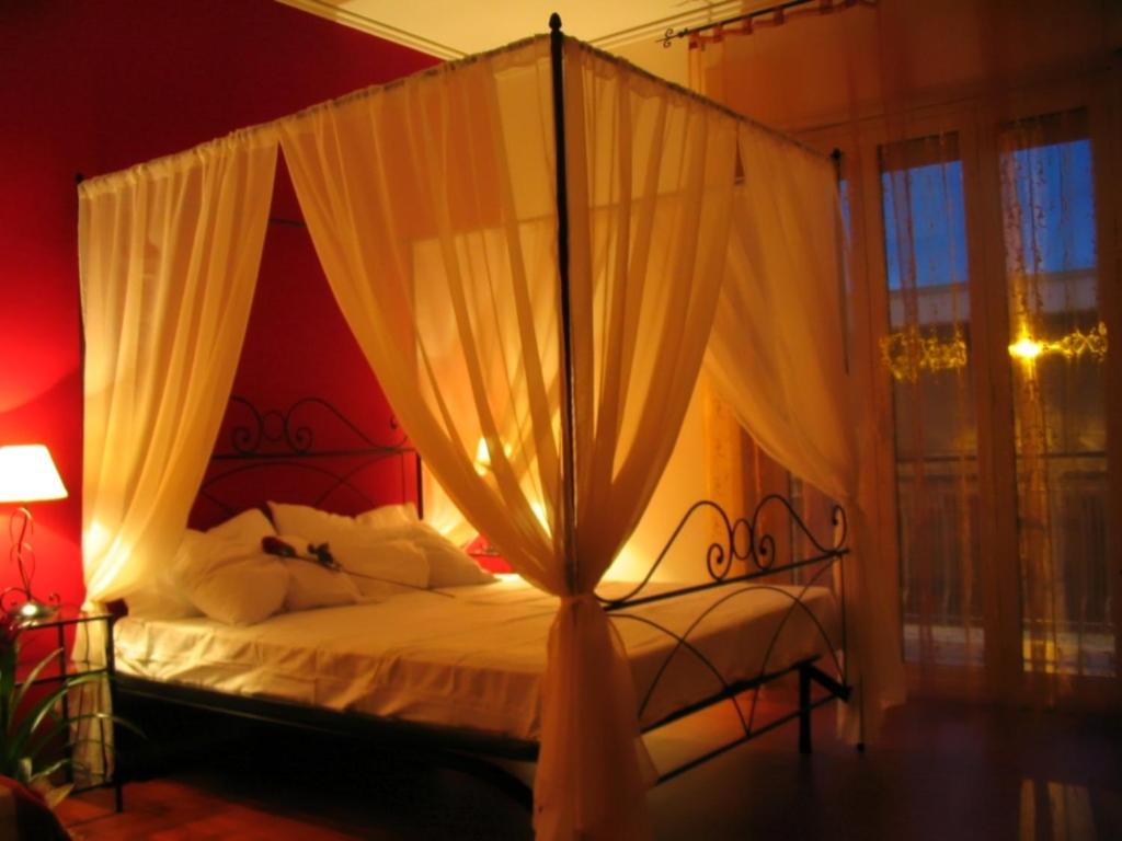 a bedroom with a canopy bed with white curtains at A Casa Olimpia B&B in Giarre