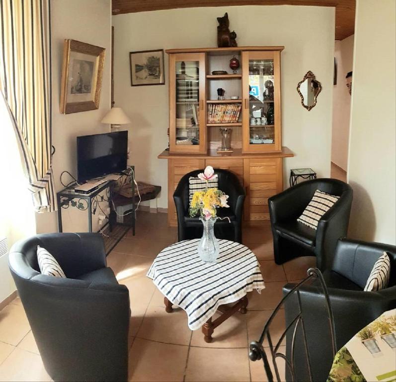uma sala de estar com cadeiras, uma mesa e uma televisão em Maison Des Lys em Jonzac