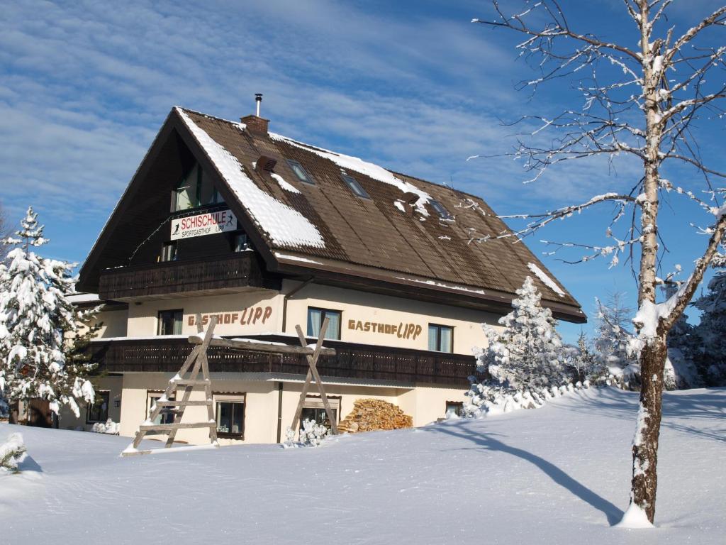 a large building with a snow covered roof in the snow at Sportgasthof Lipp in Lederwinkel