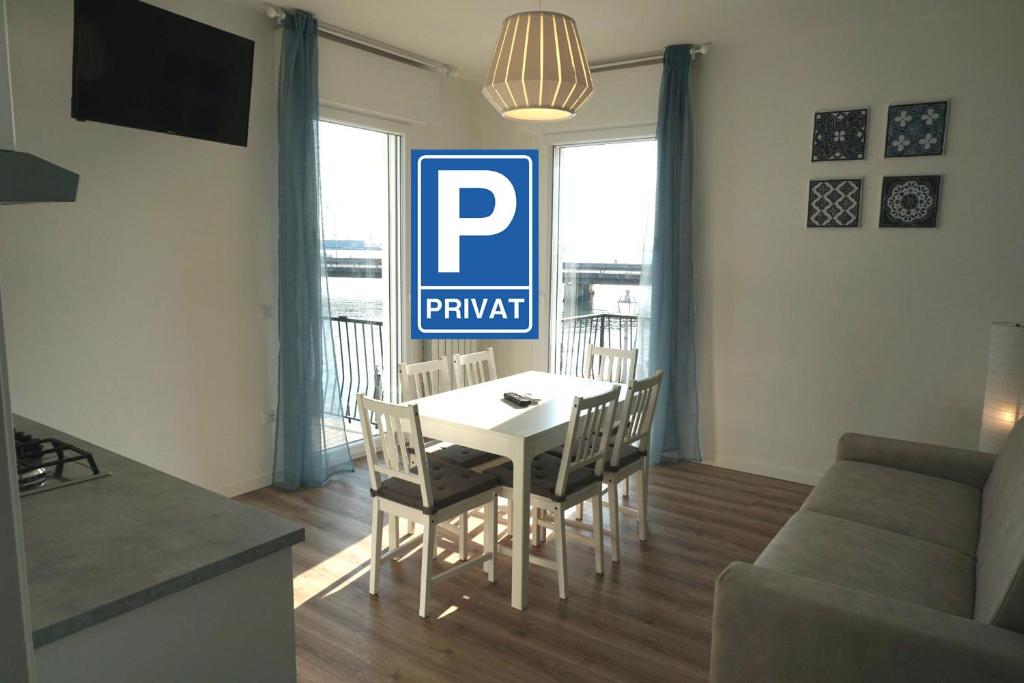 un soggiorno con tavolo e sedie e un cartello parcheggio P di Appartamento Tramonto a Chioggia