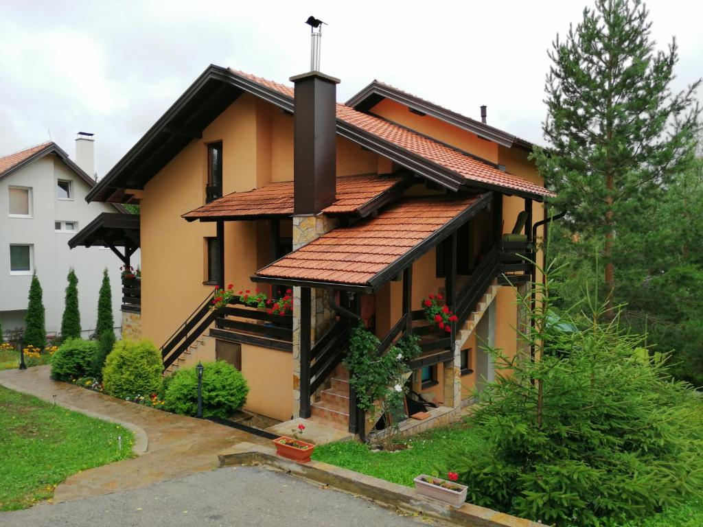 a house with a red roof and some plants at Apartments Dobra Vila in Zlatibor