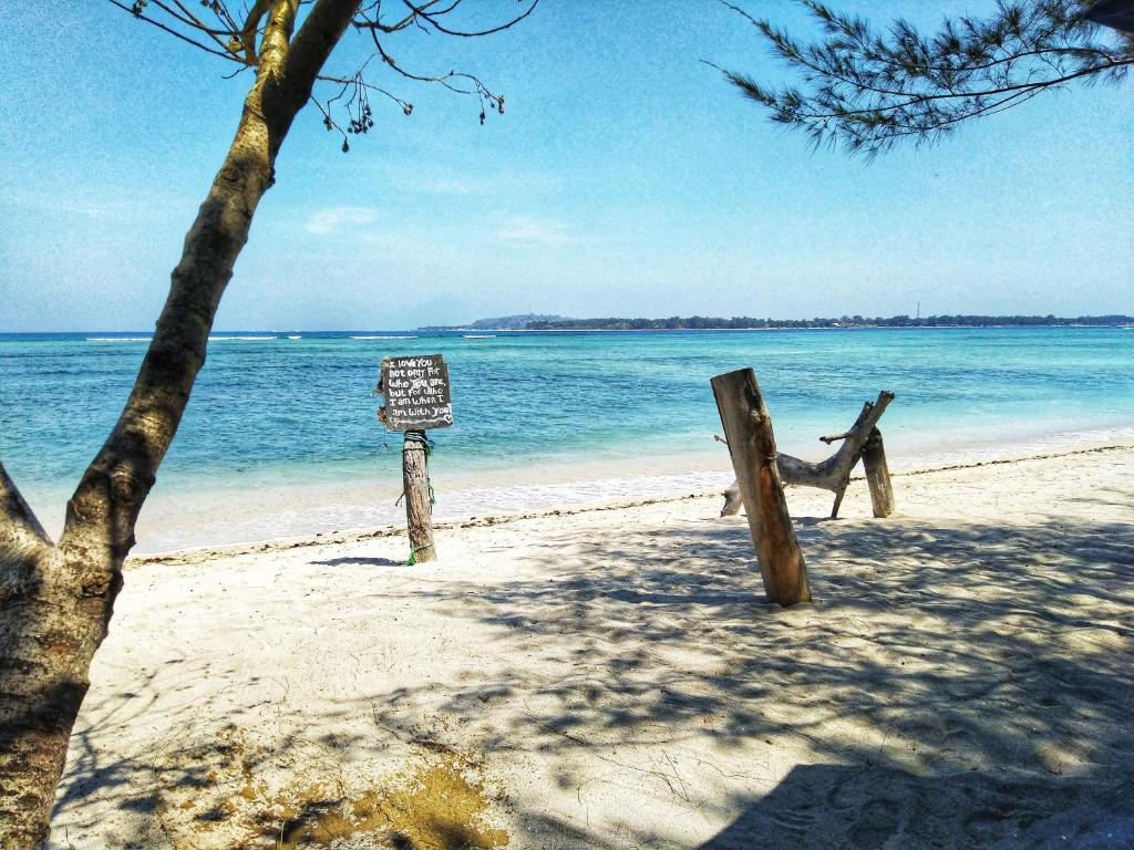 a sign on a beach next to the ocean at Adinda Bungalows in Gili Air