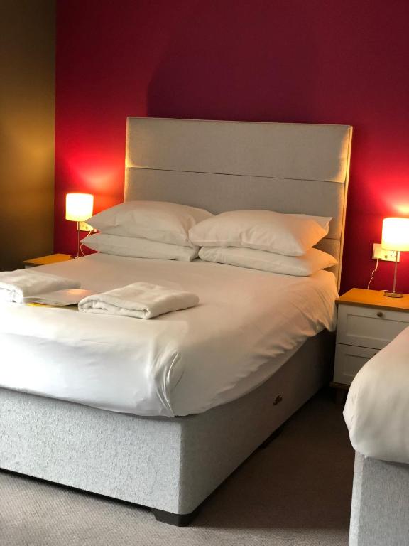 a large bed with white pillows and a red wall at B+B York in York