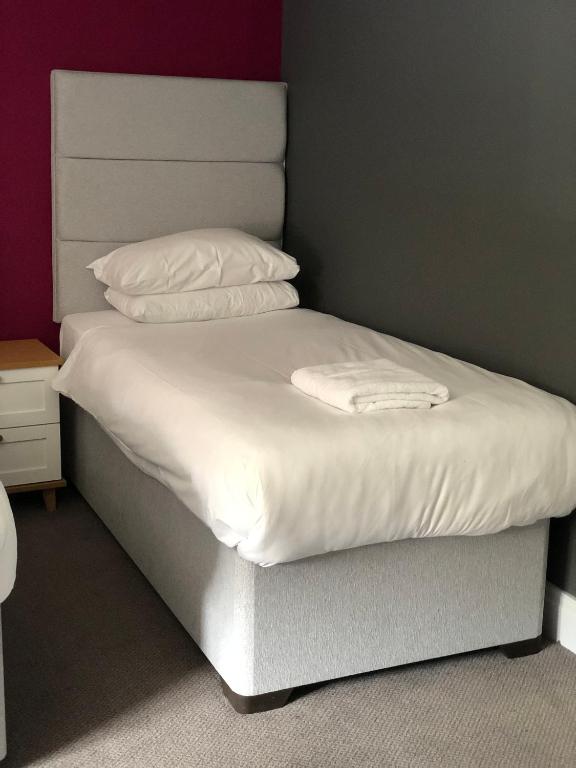 a bed with white sheets and pillows on it at B+B York in York
