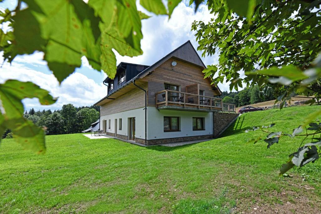 a house on top of a grassy hill at Apartmány Chata Večernice in Dolní Morava