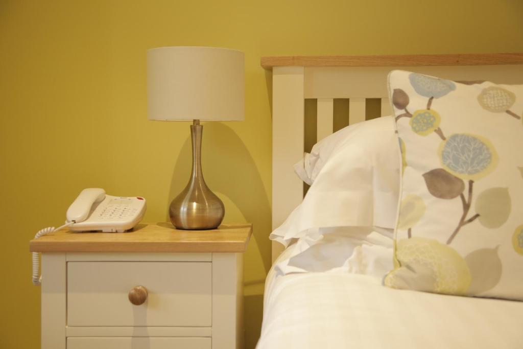 a bed with a lamp and a phone on a night stand at B+B York in York