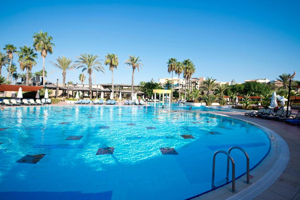 a large swimming pool with palm trees in a resort at Limak Arcadia Sport Resort Belek in Belek