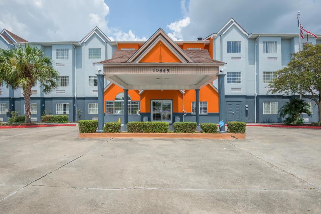 an orange and white building with palm trees at Trident Inn & Suites, Baton Rouge in Baton Rouge