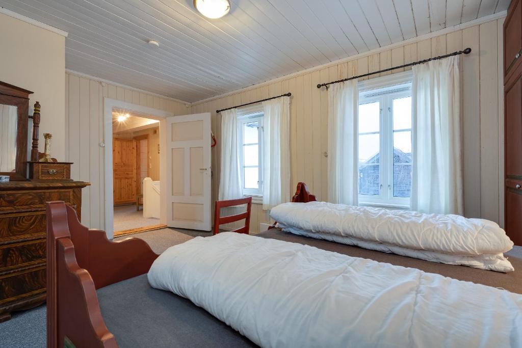 a bedroom with two beds in a room with windows at Dale Gård in Heggenes