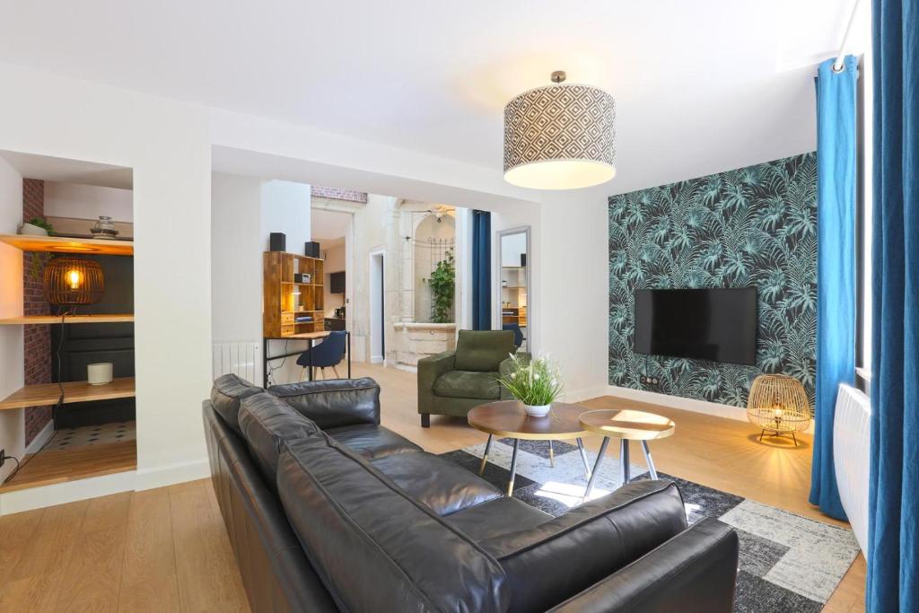 a living room with a leather couch and a tv at Le Relais DUCAL - Appartements d'Hôtes Vieille Ville in Nancy