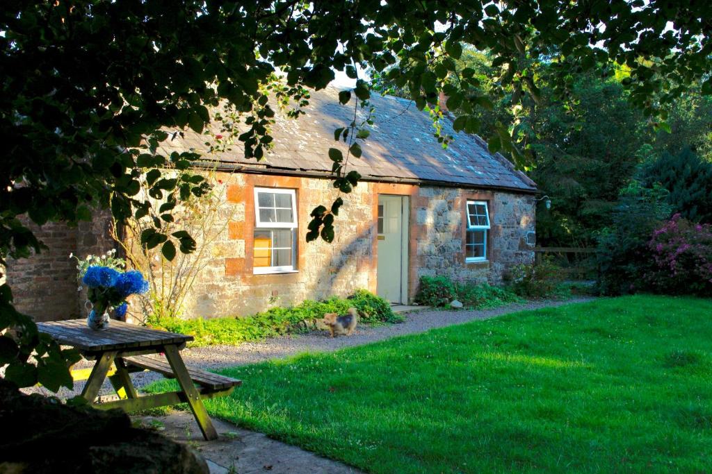 uma pequena casa de pedra com uma mesa em frente em Little Dunbar Cottage em Kirkbean