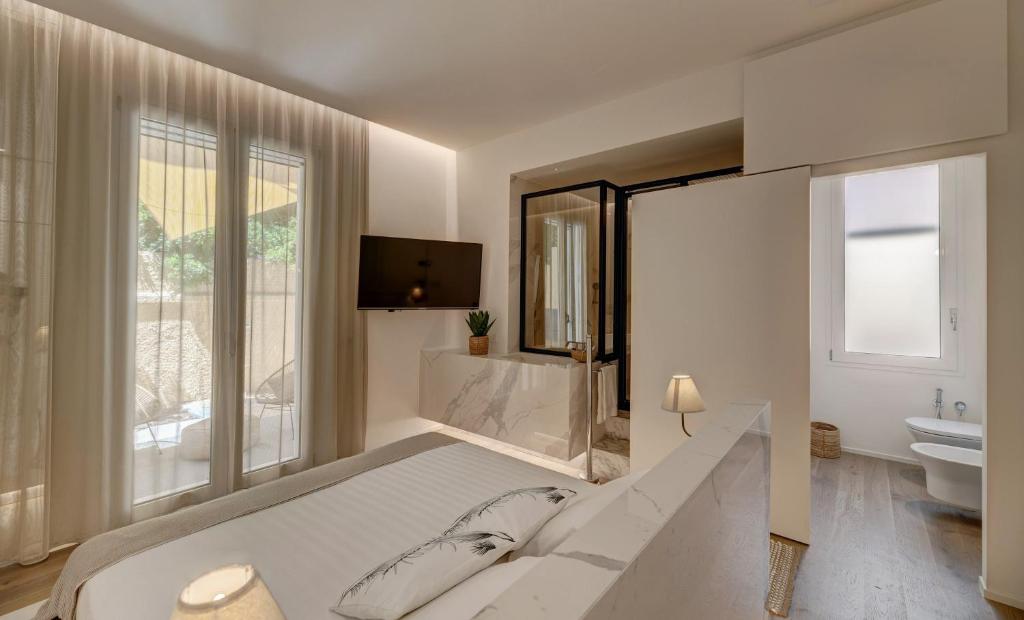 a white bedroom with a large bed and a tv at Le Palmette Suites in Cagliari