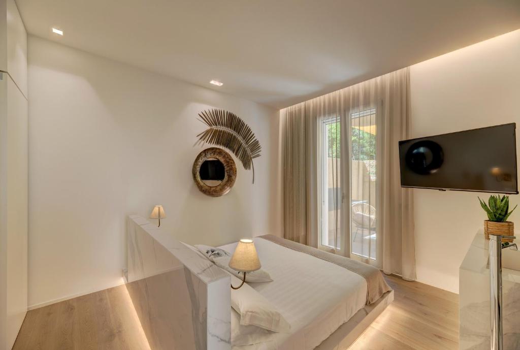 Camera bianca con letto e televisione a parete di Le Palmette Suites a Cagliari