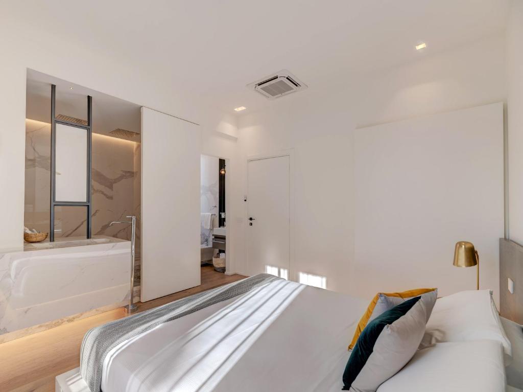 a white bedroom with a bed and a tub at Le Palmette Suites in Cagliari