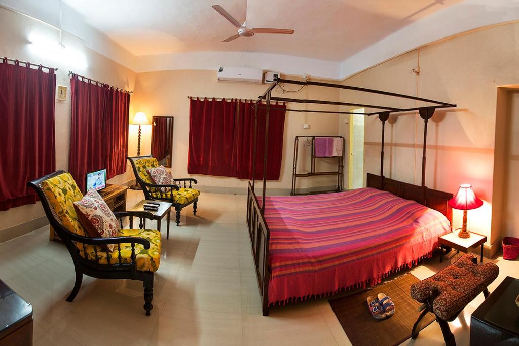a bedroom with a canopy bed and a living room at Judges Court in Puri