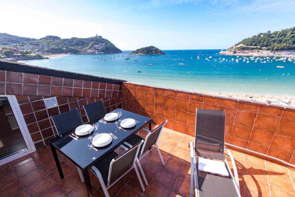 un tavolo e sedie su un balcone con vista sulla spiaggia di The Rentals Collection | Costa a San Sebastián