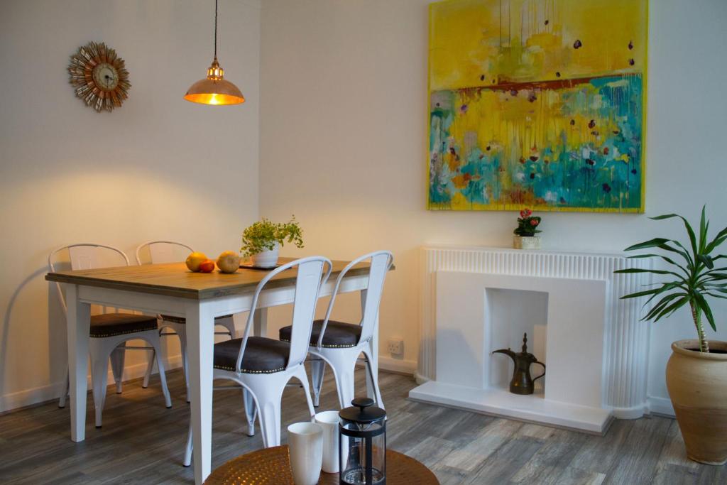 ein Esszimmer mit einem Tisch, Stühlen und einem Kamin in der Unterkunft Baker Street Style in London