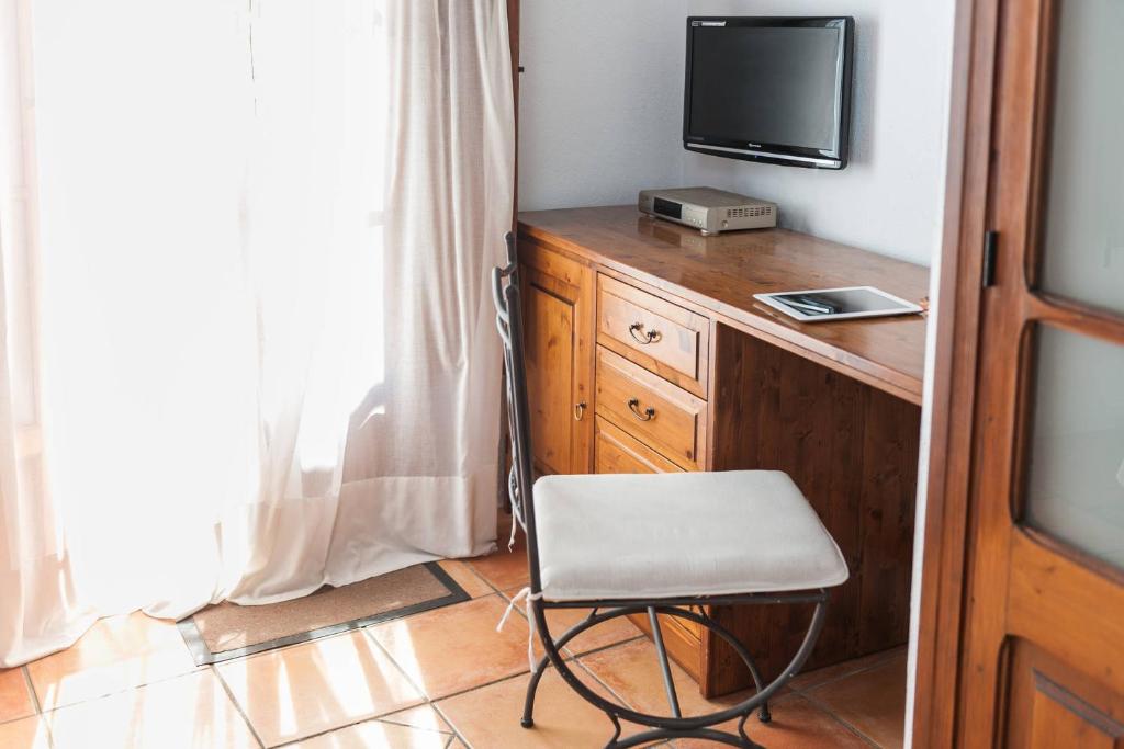 a room with a desk with a chair and a television at Hotel Can Simo in Alcudia