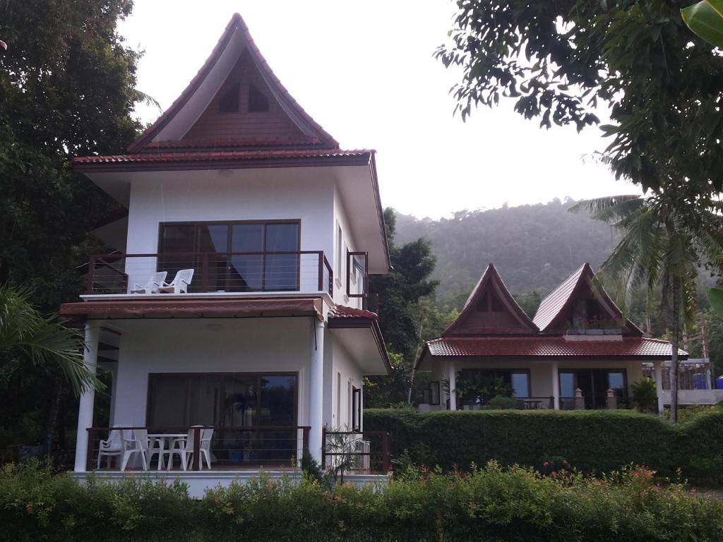 uma casa branca com um telhado com mesas e cadeiras em Tulip Villa Oceanview em Ko Chang