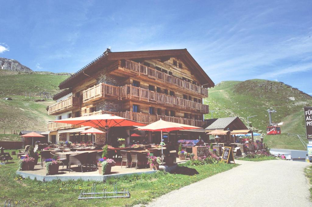 ein Gebäude mit Tischen und Sonnenschirmen davor in der Unterkunft Hotel Alpina in Fiesch