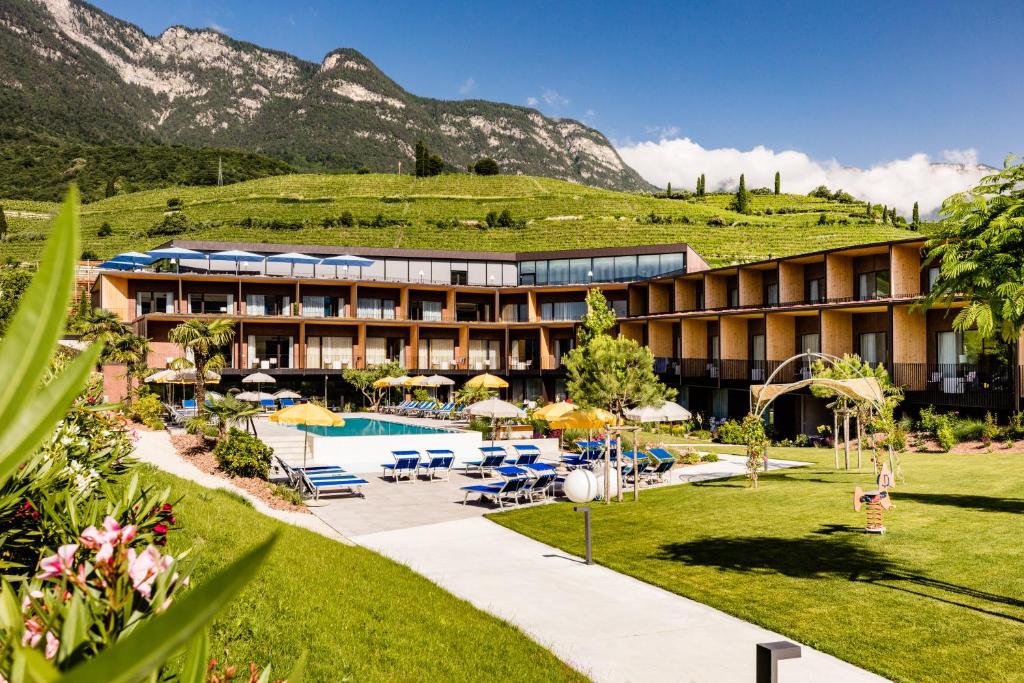 un complejo con piscina y montañas de fondo en Hotel Thalhof am See en Caldaro