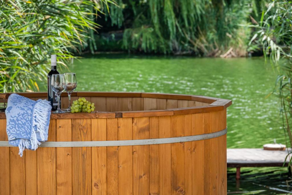 a wooden hot tub with a glass of wine and grapes at Vadszőlő Apartmanház Gyomaendrőd in Gyomaendrőd