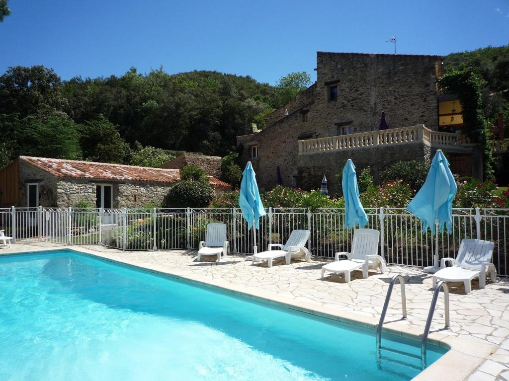 a pool with chairs and umbrellas in front of a building at La Terrasse in Reynès