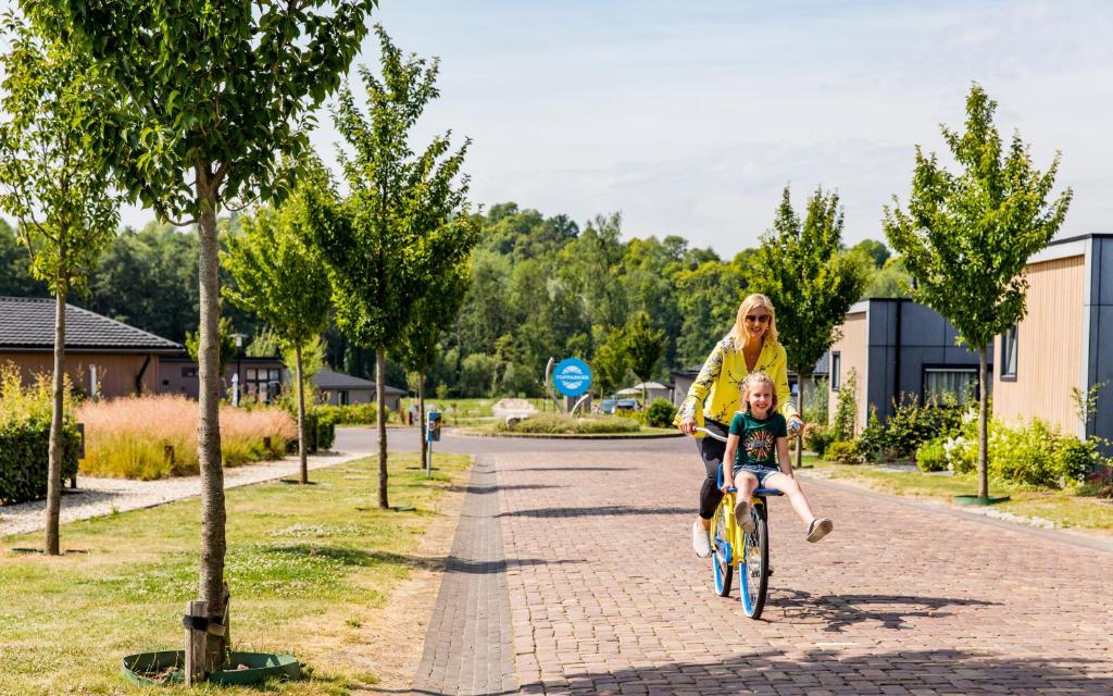 una mujer montando una bicicleta con un niño en ella en TopParken – Résidence Valkenburg, en Valkenburg