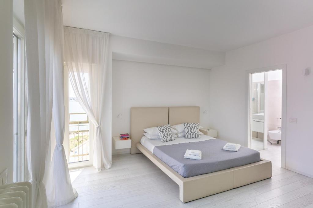 a white bedroom with a bed and a large window at Santa Rosa luxury apartment 2 BEDROOMS 4 People private parking in Trani