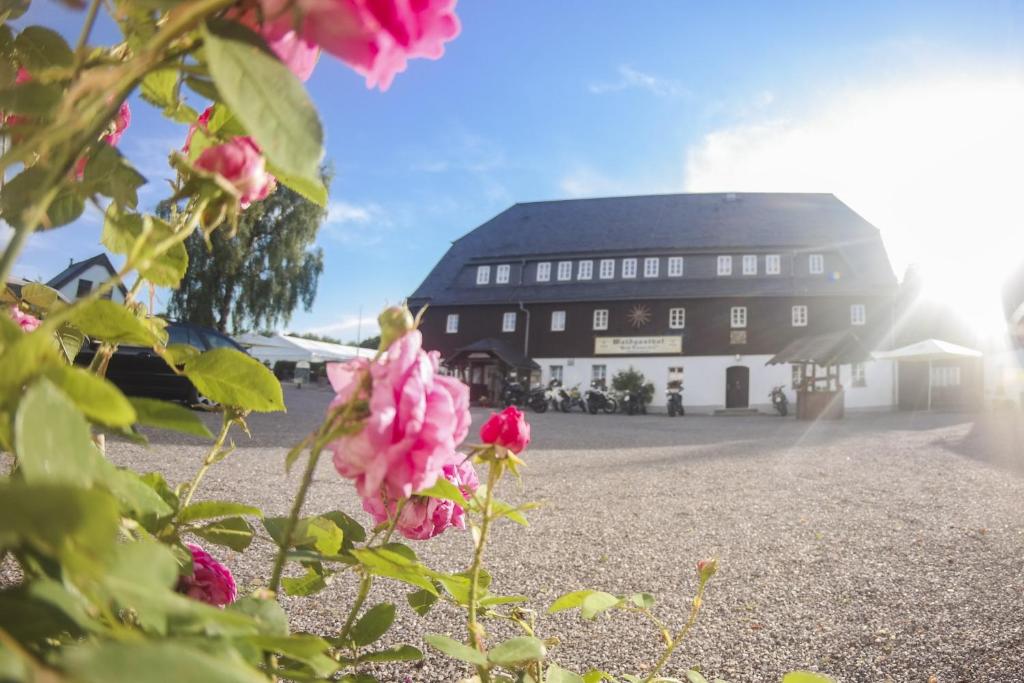 ein schwarzes Gebäude mit rosa Blumen davor in der Unterkunft Waldgasthof Bad Einsiedel in Seiffen