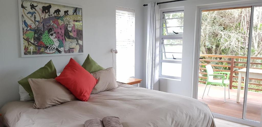 um quarto com uma cama com almofadas vermelhas e verdes em Buccaneers on the beach, Chintsa, South Africa em Chintsa