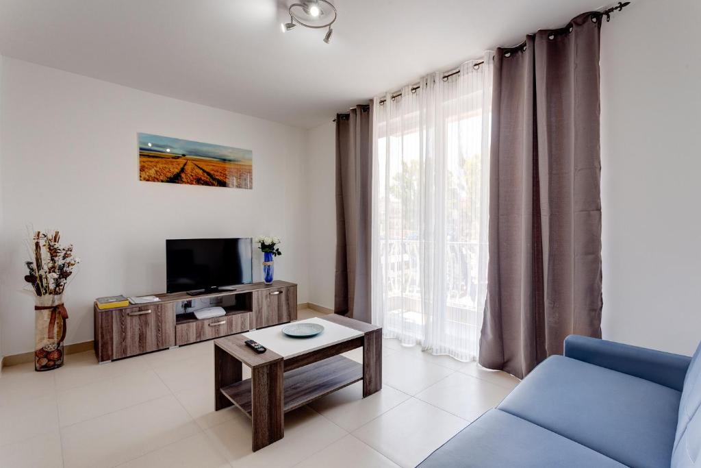 a living room with a blue couch and a tv at Harmony Apartments in Msida