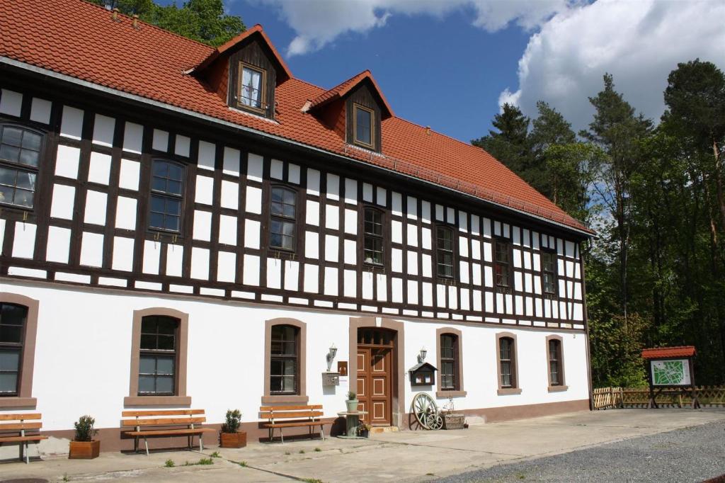 a black and white building with benches in front of it at Zu den grauen Ziegenböcken in Serba