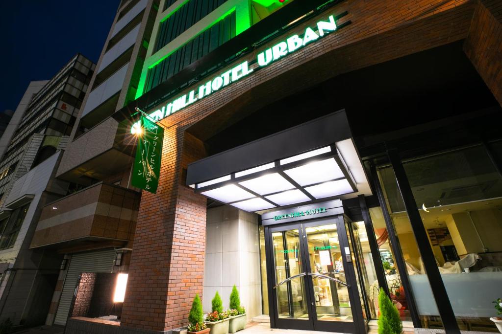 a store front of a building with a green neon sign at Green Hill Hotel Urban in Kobe