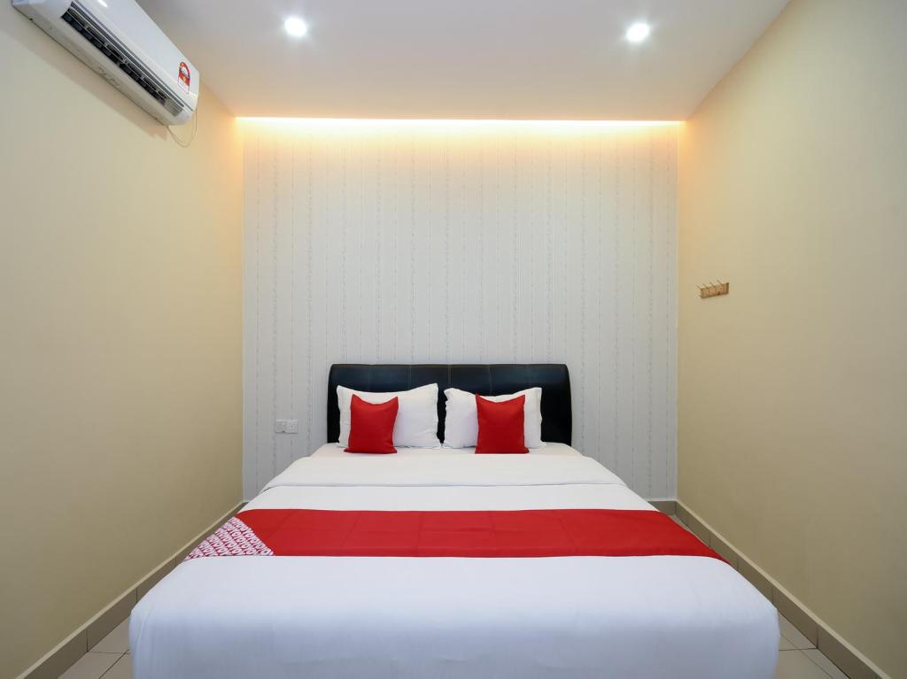 una camera da letto con un grande letto con cuscini rossi di OYO 89301 Ys Inn a Miri