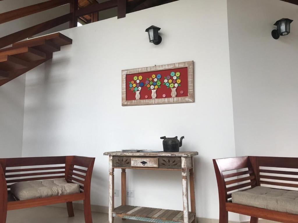 2 Stühle und ein Tisch mit einem Bild an der Wand in der Unterkunft Pouso Alcantara in Paraty