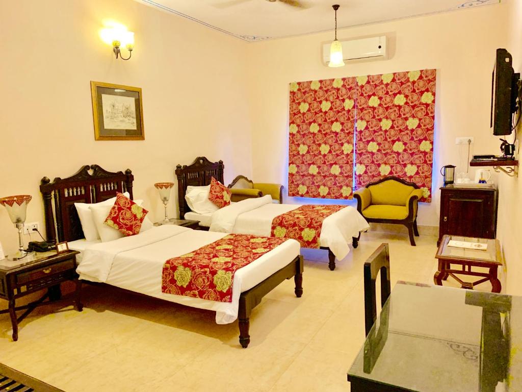 a hotel room with two beds and a window at Suryaa Villa - A Boutique Heritage Hotel in Jaipur
